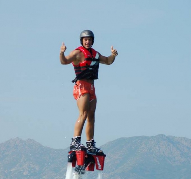 boy with vest and helmet standing on a flyboard platform 